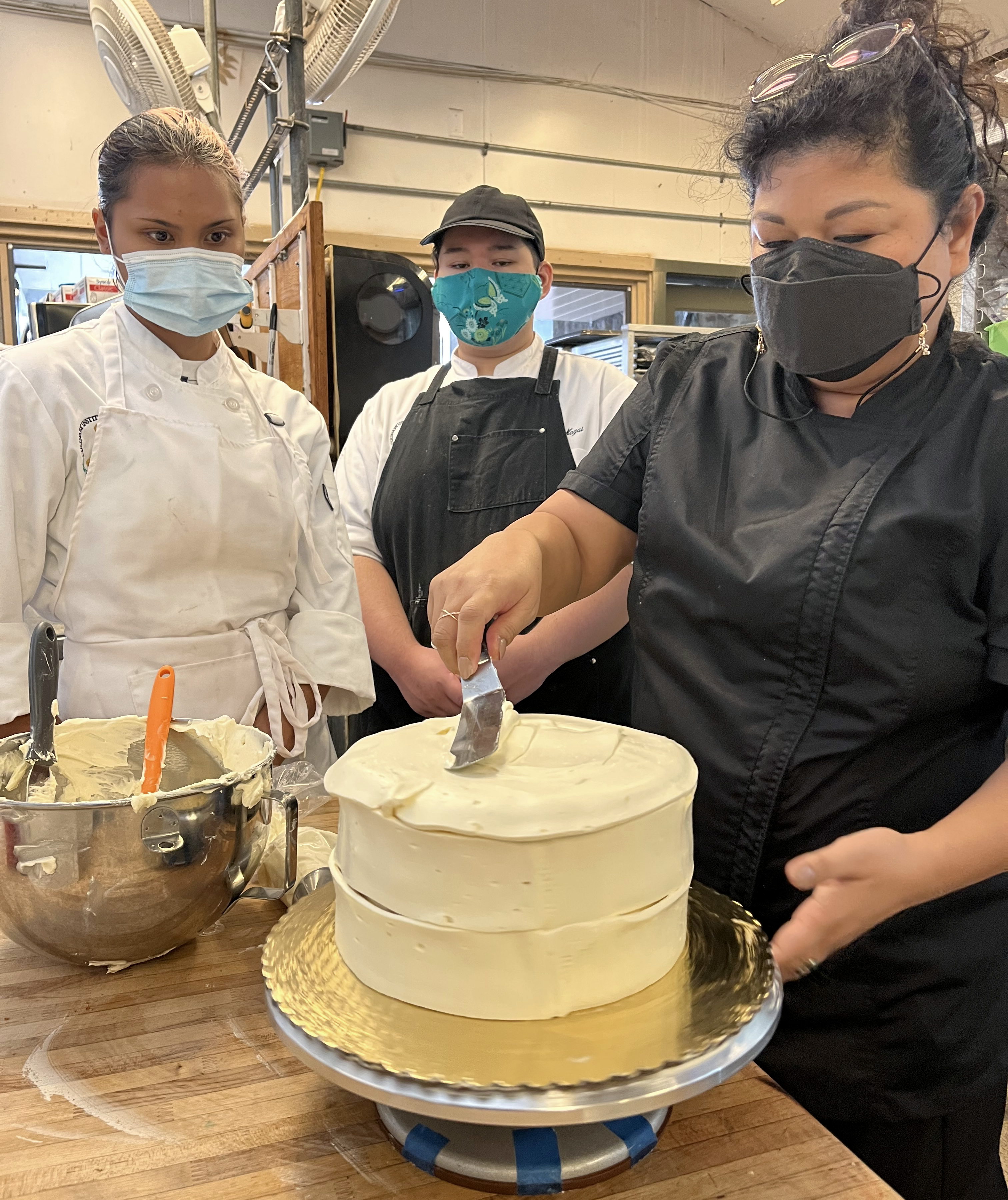 Maria Short, owner of Short N Sweet Bakery in Hilo, gives a demonstration to Hawaii Community College Culinary Arts students Sydirah Aricayos, left, and Ka’io Nagui. 